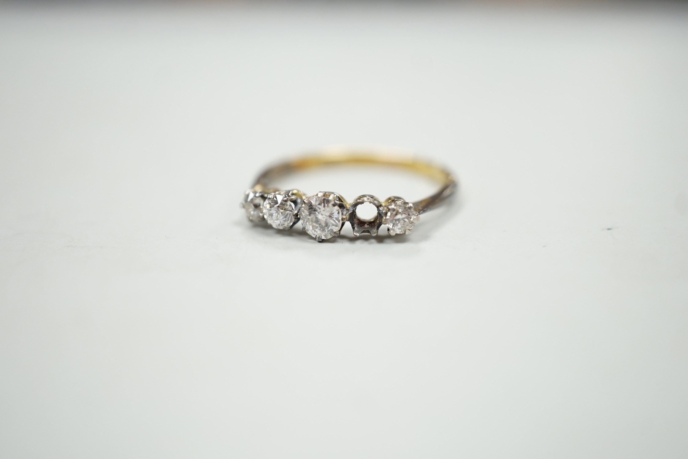 An 18ct and graduated five stone diamond set half hoop ring, size P, gross weight 1.9 grams, one stone loose but present.